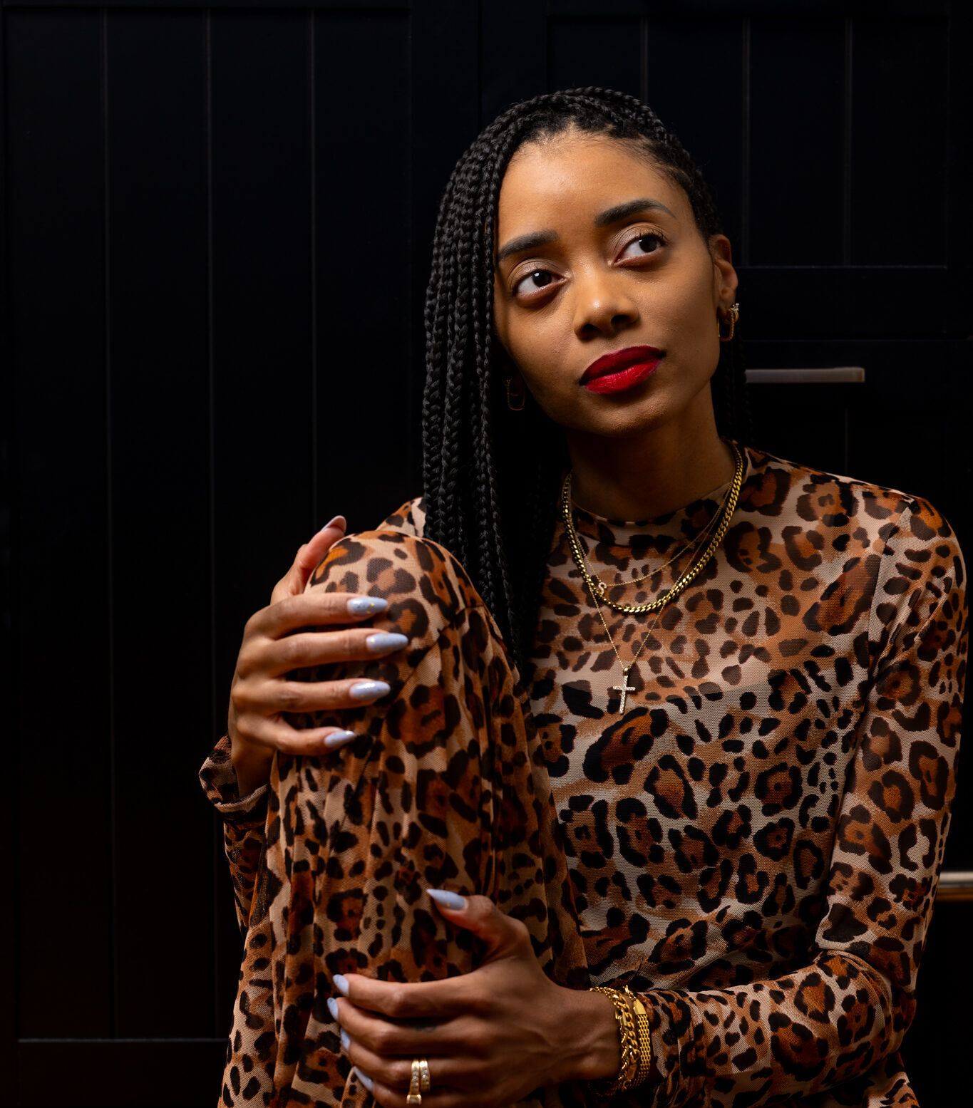 Photo of Shanika sitting on the floor with a leopard dress and black background.