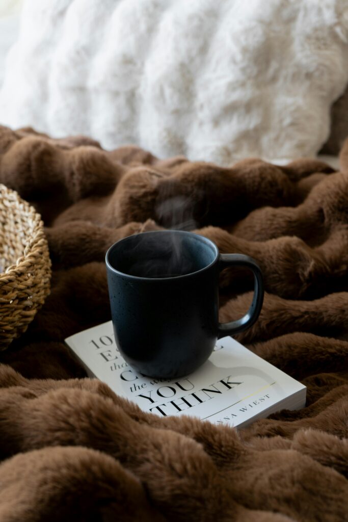 Image of a mug on a bed with a brown blanket.