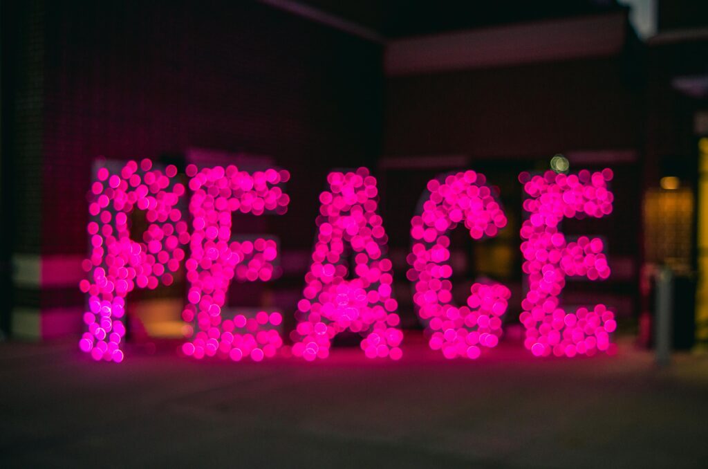 Image of a pink lit sign that says Peace.