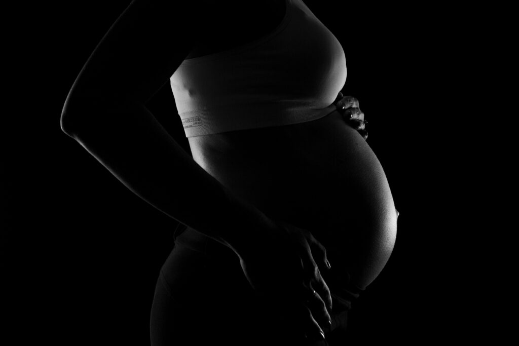 Image of a woman holding her large pregnant belly in black and white.