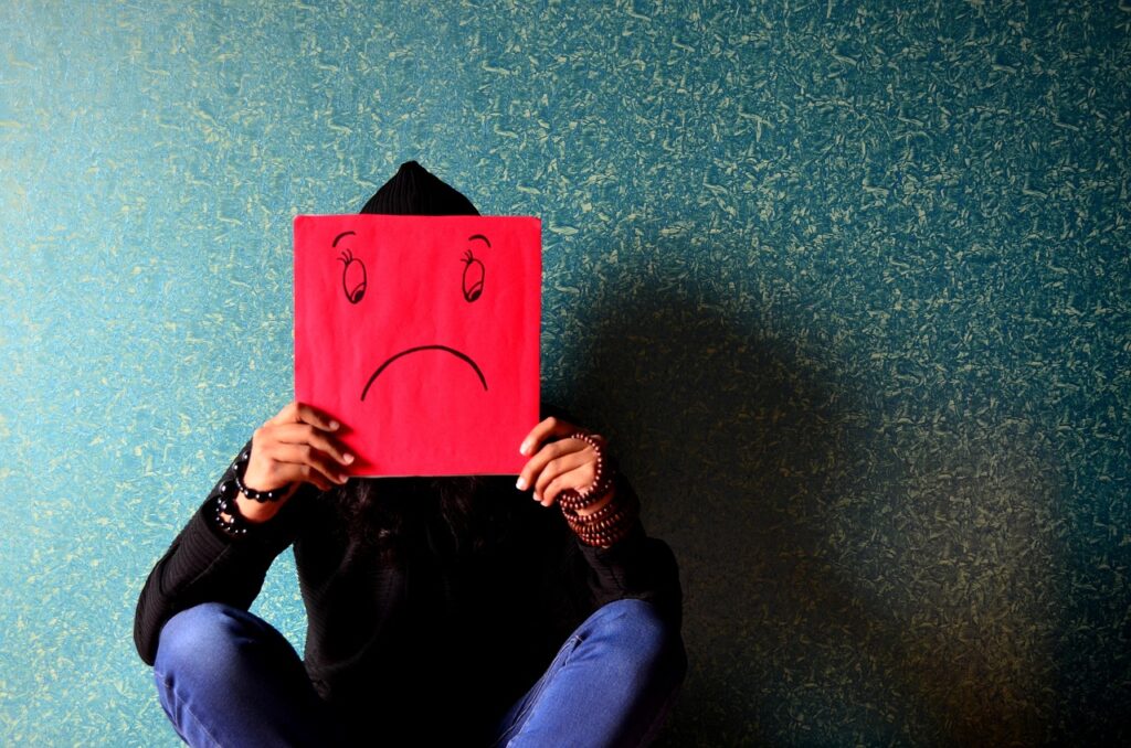 Image of a person sitting with a red sign of a sad face.