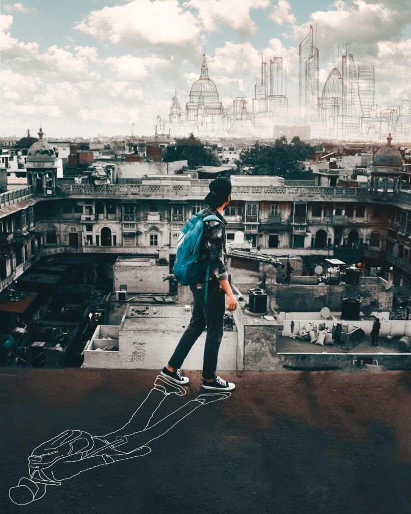 Young man standing on a hill looking out at the city.