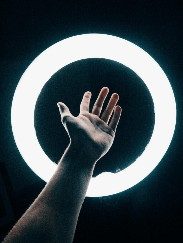 A hand reaching into a light ring.