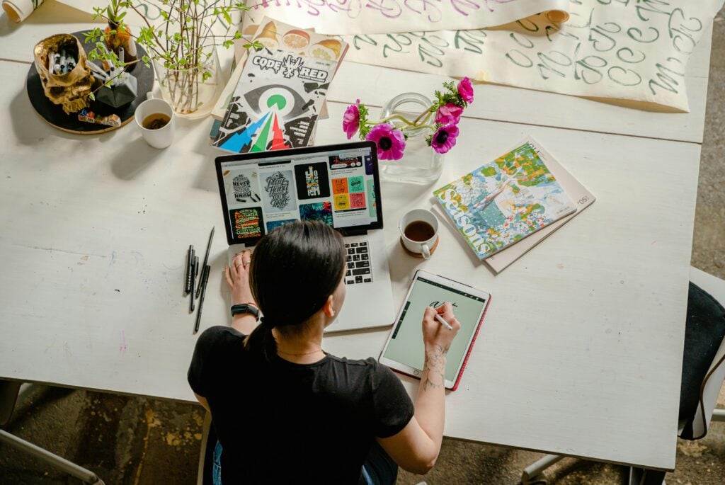 Image of a woman working at a desk with a laptop and papers.