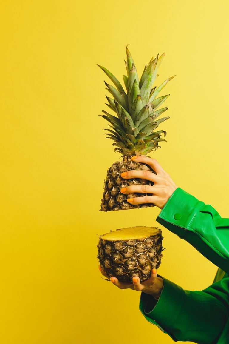 Image of someone holding a pineapple cut in half.