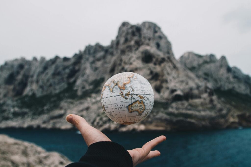 Image of a hand holding a world globe in their hand and throwing it the air slightly.