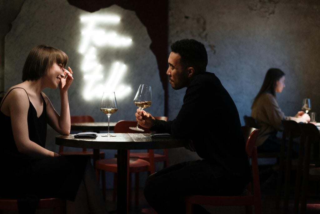 An image of two people at a restaurant table drinking wine.