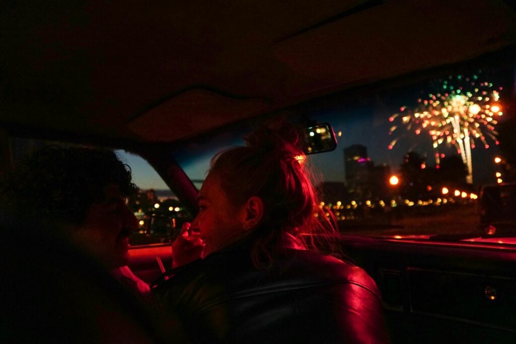 Image of couple in a car at night with fireworks.
