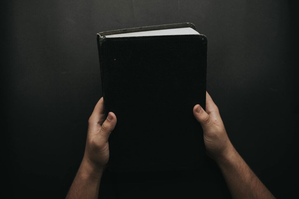 Man hands holding up a black bible.