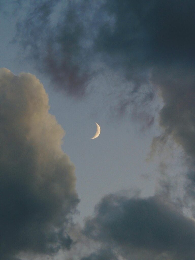 Clouds in a night sky with a crescent moon.