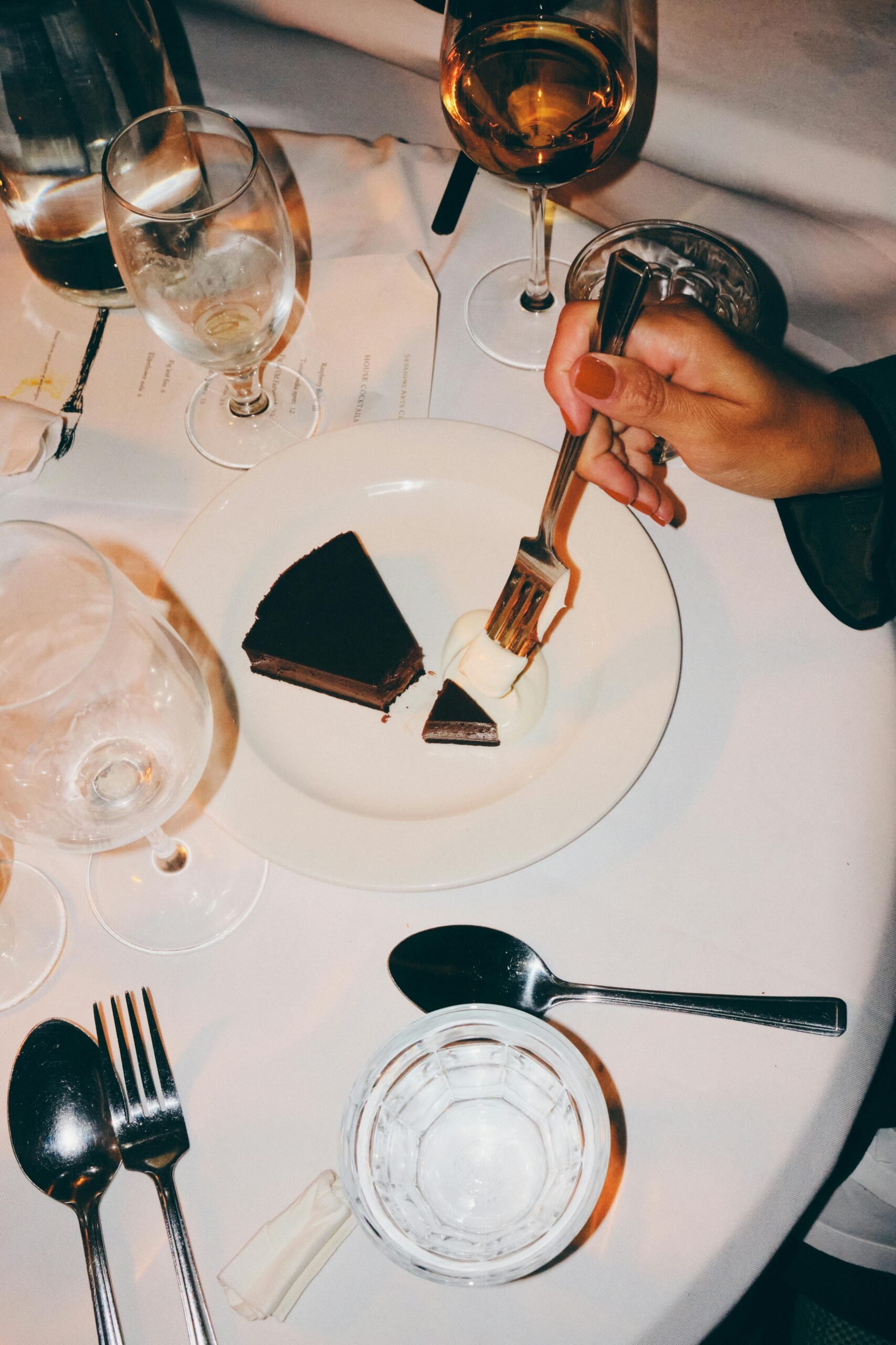 Woman hands with a fork about to eat dessert at a restaurant table.