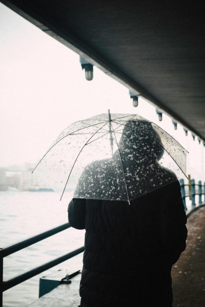 Someone walling with a black coat and umbrella.