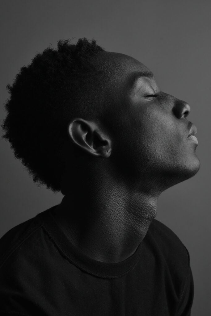 Image of a man in black closing his eyes while faced to the side.