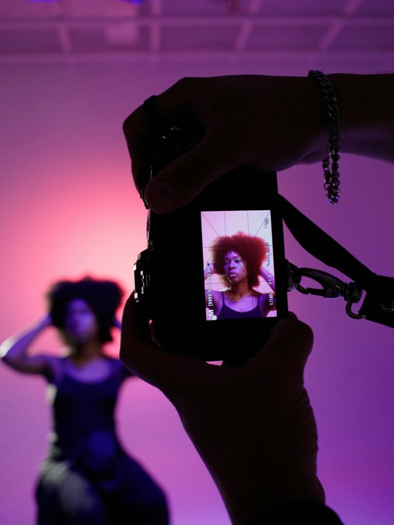 A woman being photographed with a purple background/lighting.