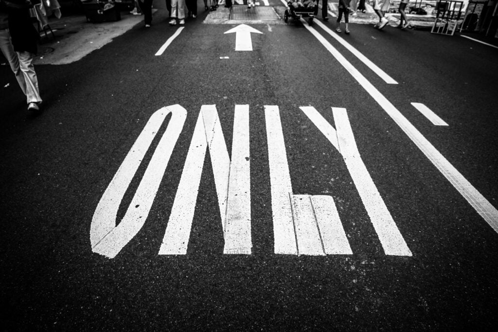 A sign on the street that has an arrow with the words "only".