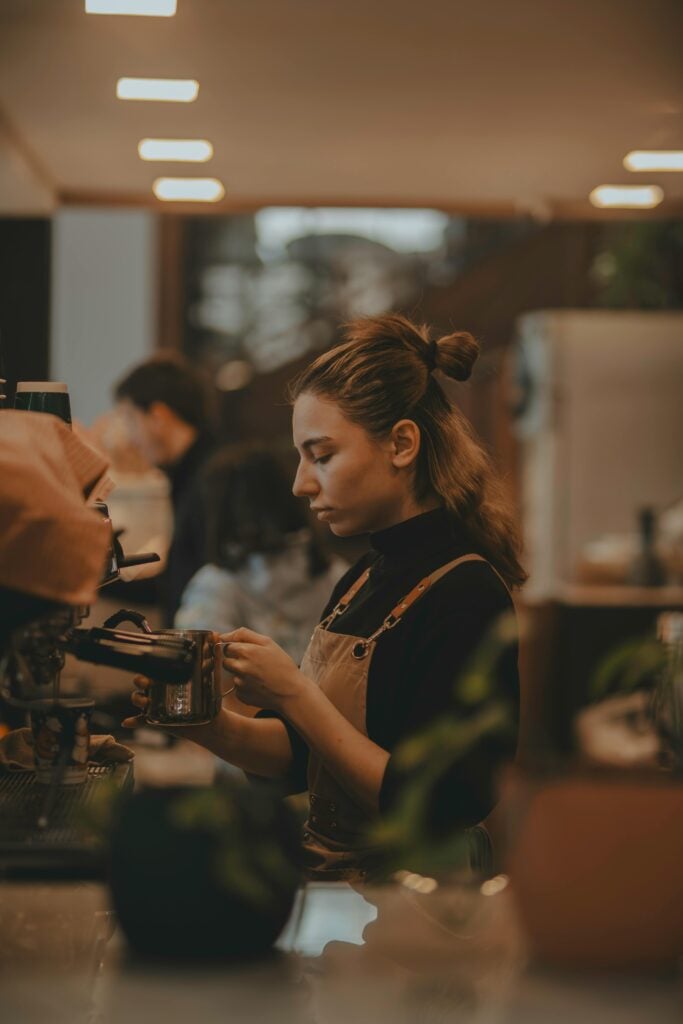 A woman in a coffee shop dressed in her uniform at work.