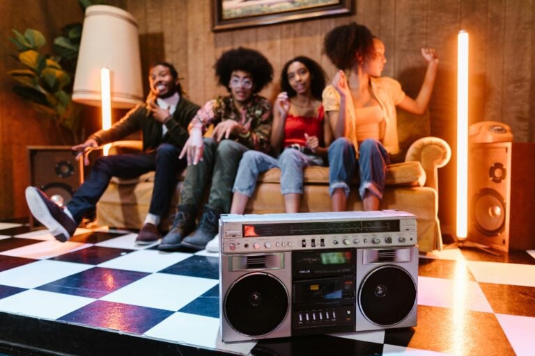 Group of friends sitting on a couch with black white tile floors and a speaker radio.