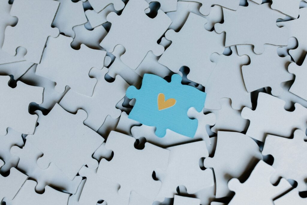 A puzzle piece with a heart atop other puzzle pieces.