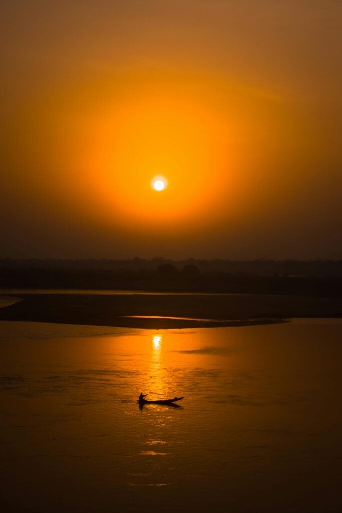 A sunset with a view of the ocean and a boat.
