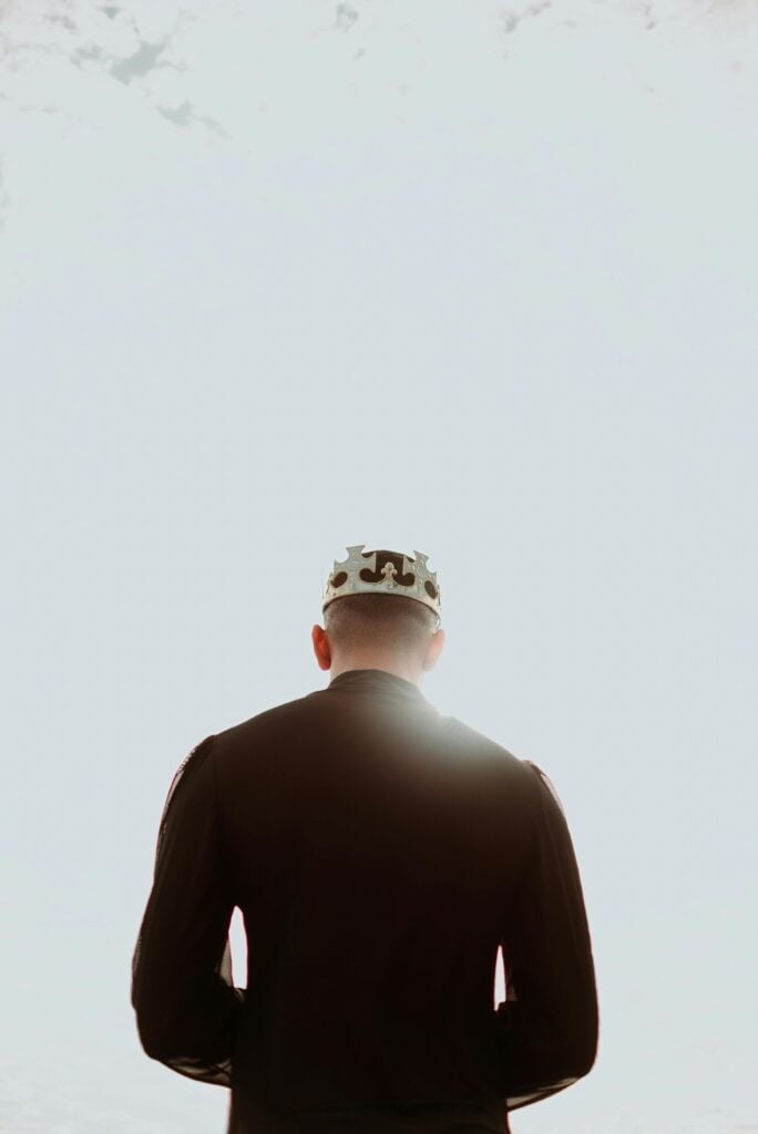 A man standing in front of a white light with a crown on his head. 