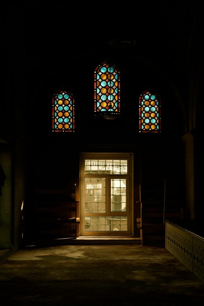 Inside look at a church in the dark with stained glass windows.
