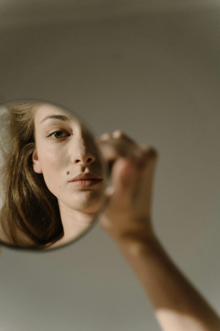 A female holding a mirror and looking at her reflection.