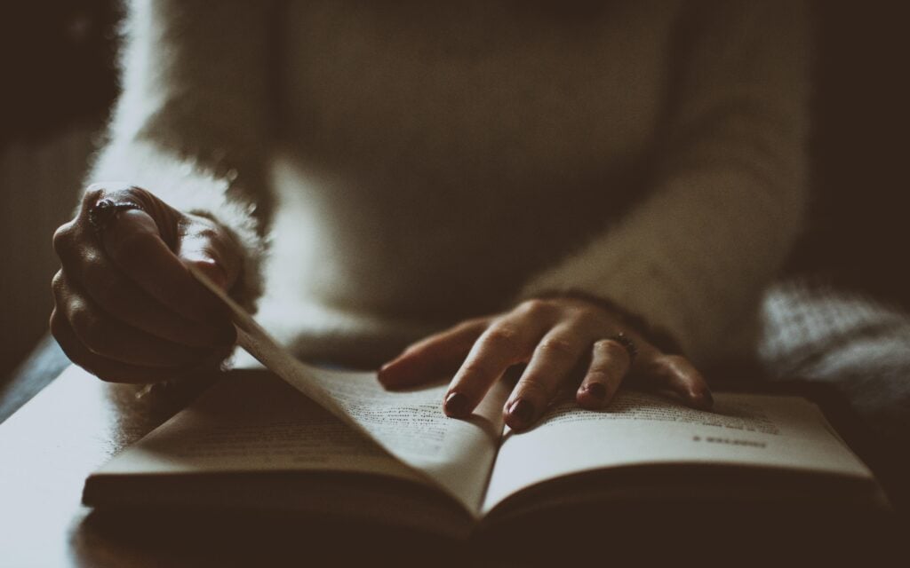 A woman looking through and reading a book.
