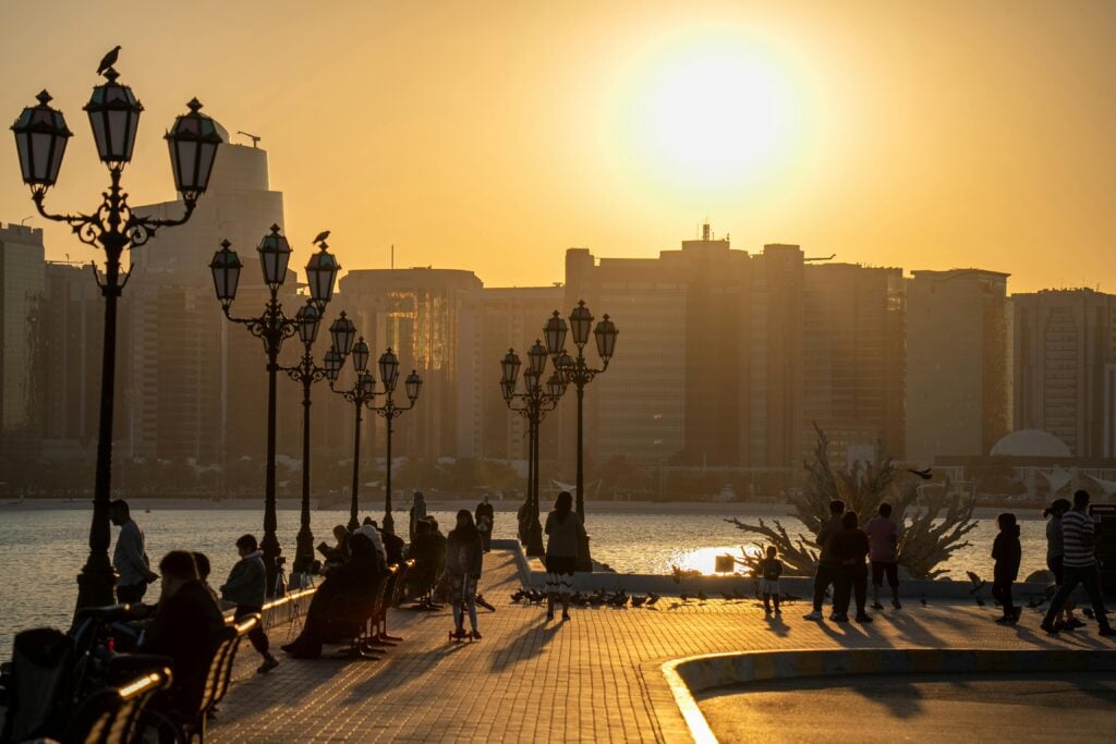 A boardwalk full of people during a sunset.