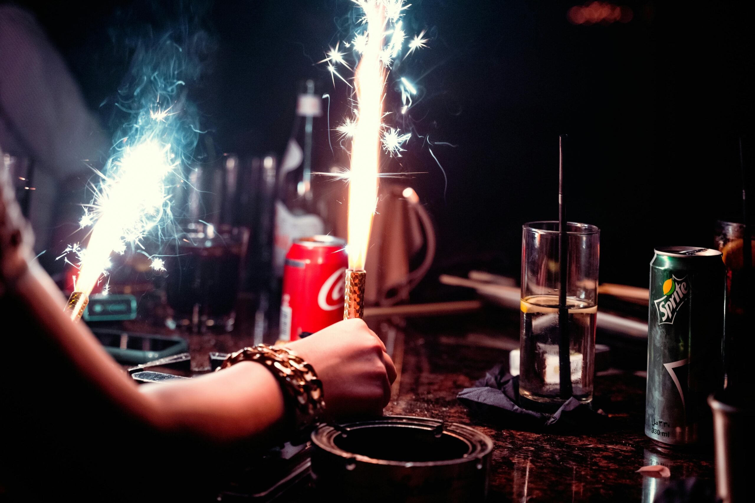 People at a table with celebratory candles, lights, and sodas.