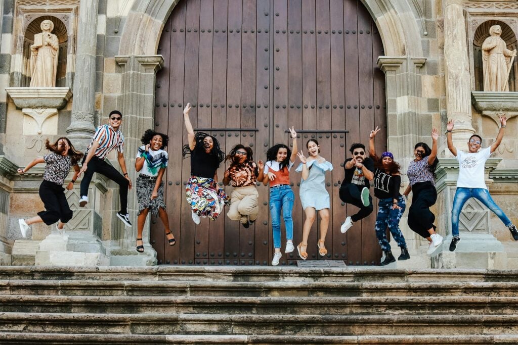 A group of young people jumping and excited in front of a church.