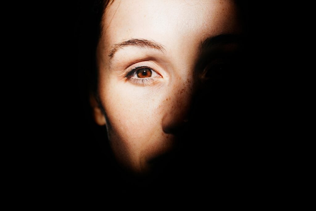 A woman's face halfway in light and halfway in darkness.