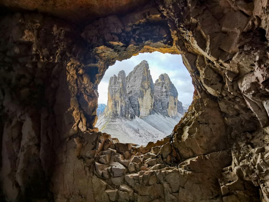 A view of mountains through a hole in a rocky area or cave.