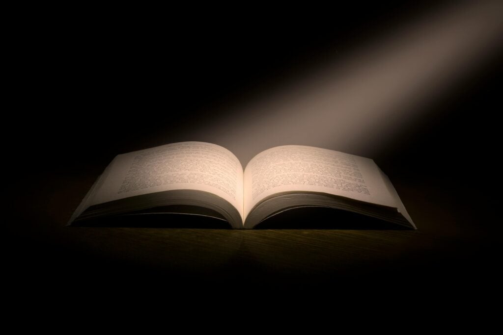 Open scriptures with a light beaming onto the pages.