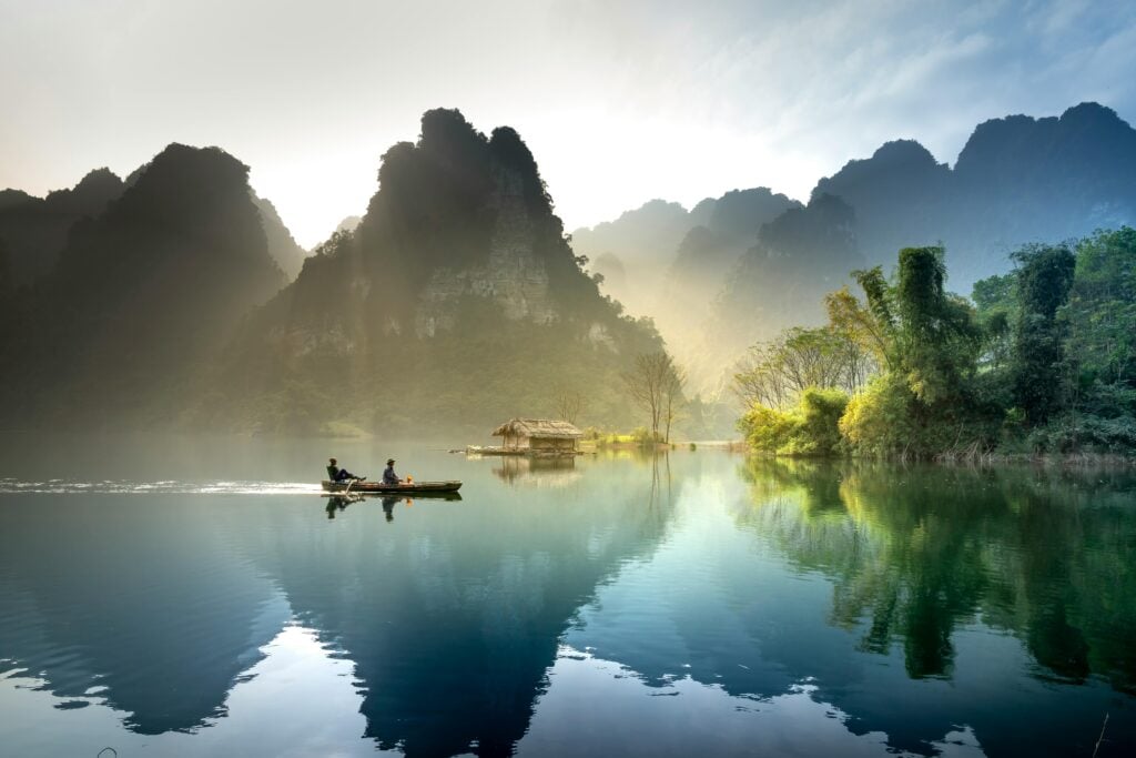 A beautiful scene of a small boat with people on water with mountains in the background.