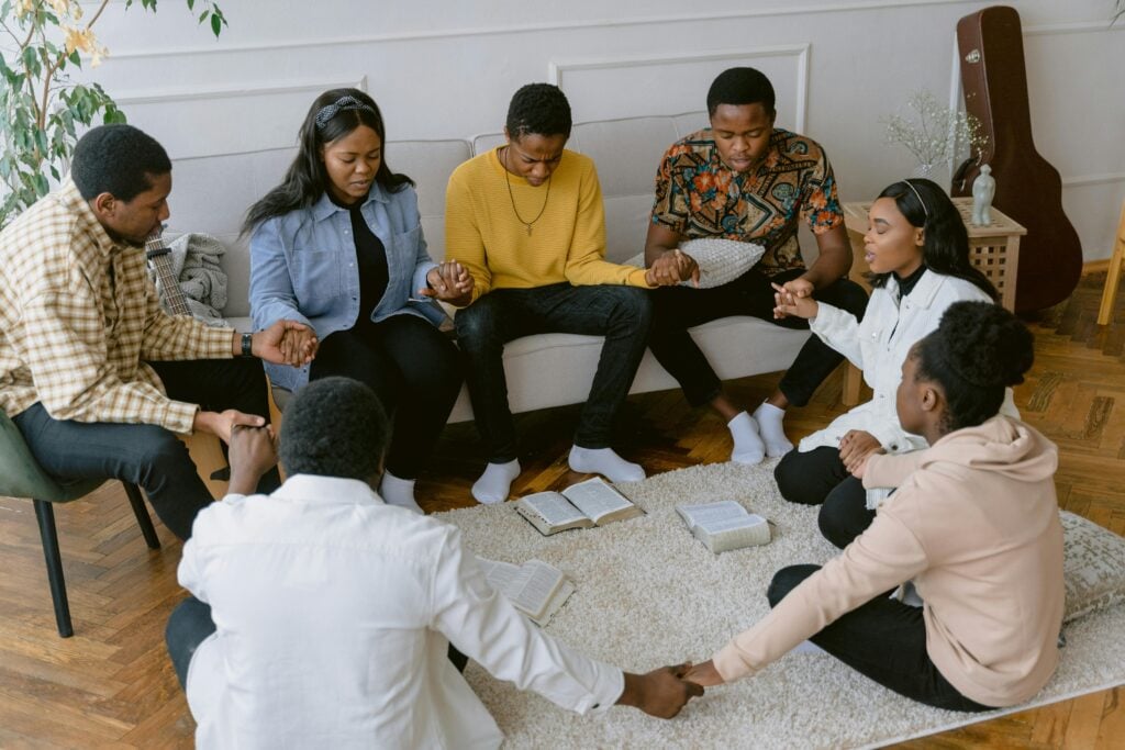 A small group of believers praying and reading the Word in their living room.