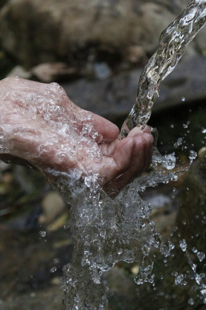 Someone hands being washed with water.