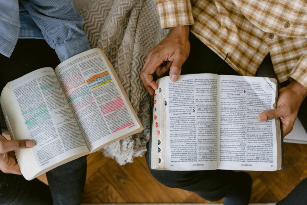 Two people sitting with open bibles reading the scriptures.