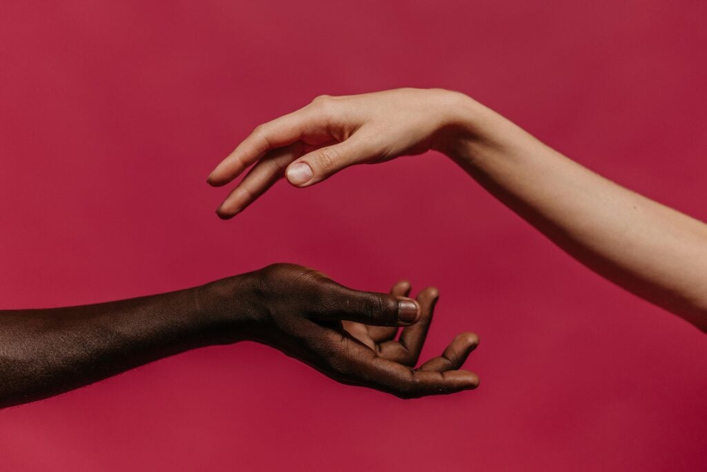 Two hands in motion of holding each other with a red background.