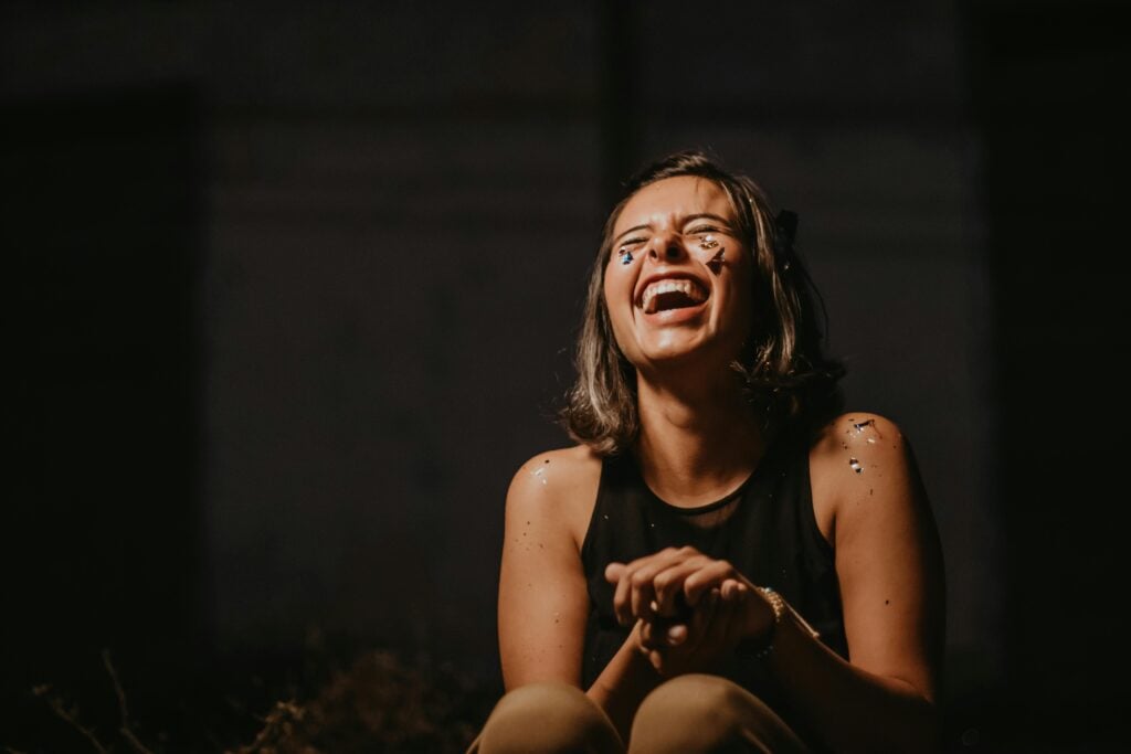 A woman looking up with eyes closed in laughter.