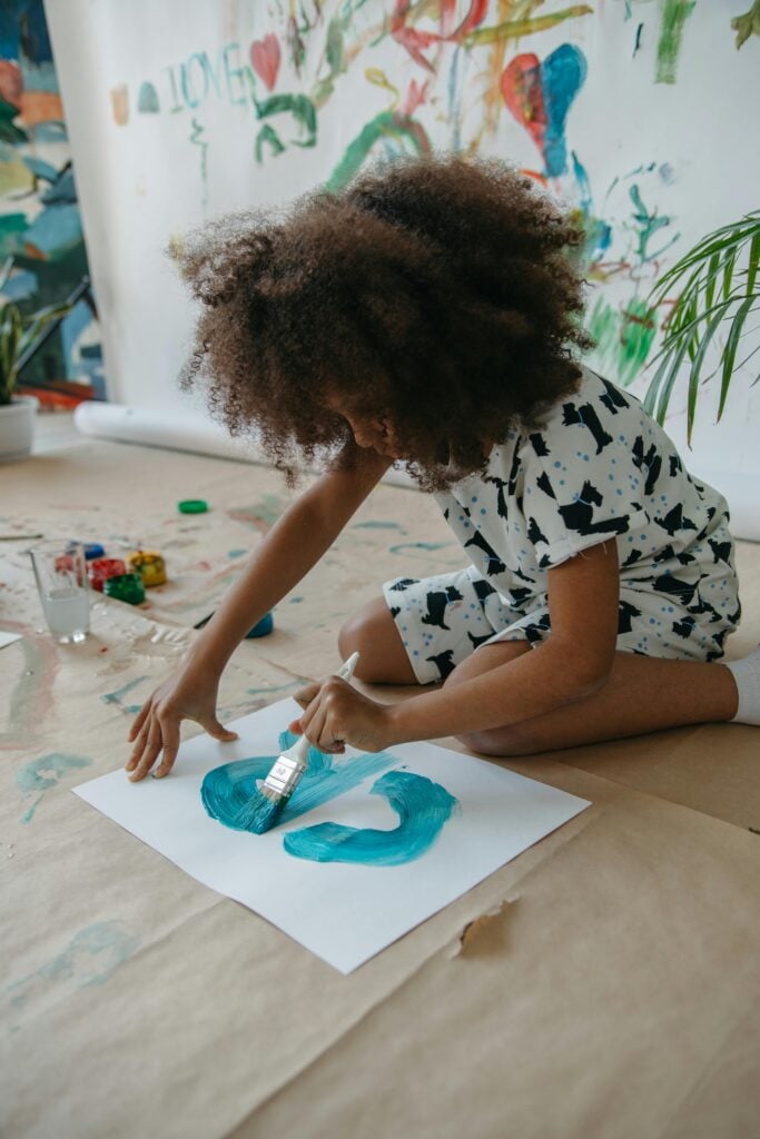 A boy sitting on the floor painting.