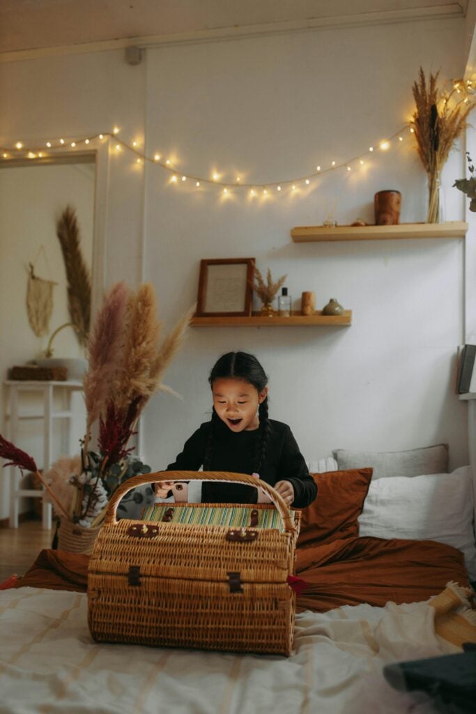 A little girl on her bed opening a wooden box with surprise. 