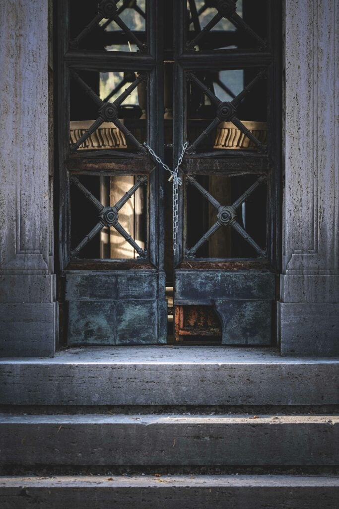 A wooden door on steps with chains.