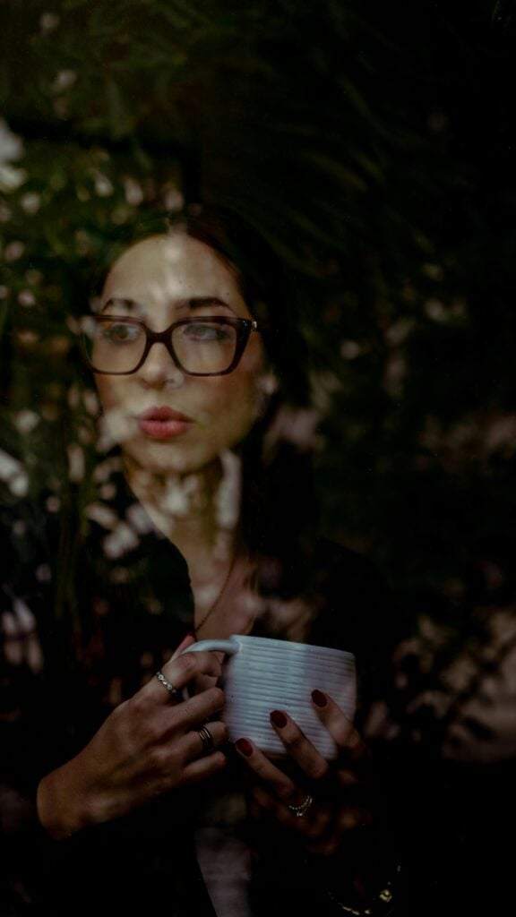 A woman holding a mug looking out the window.
