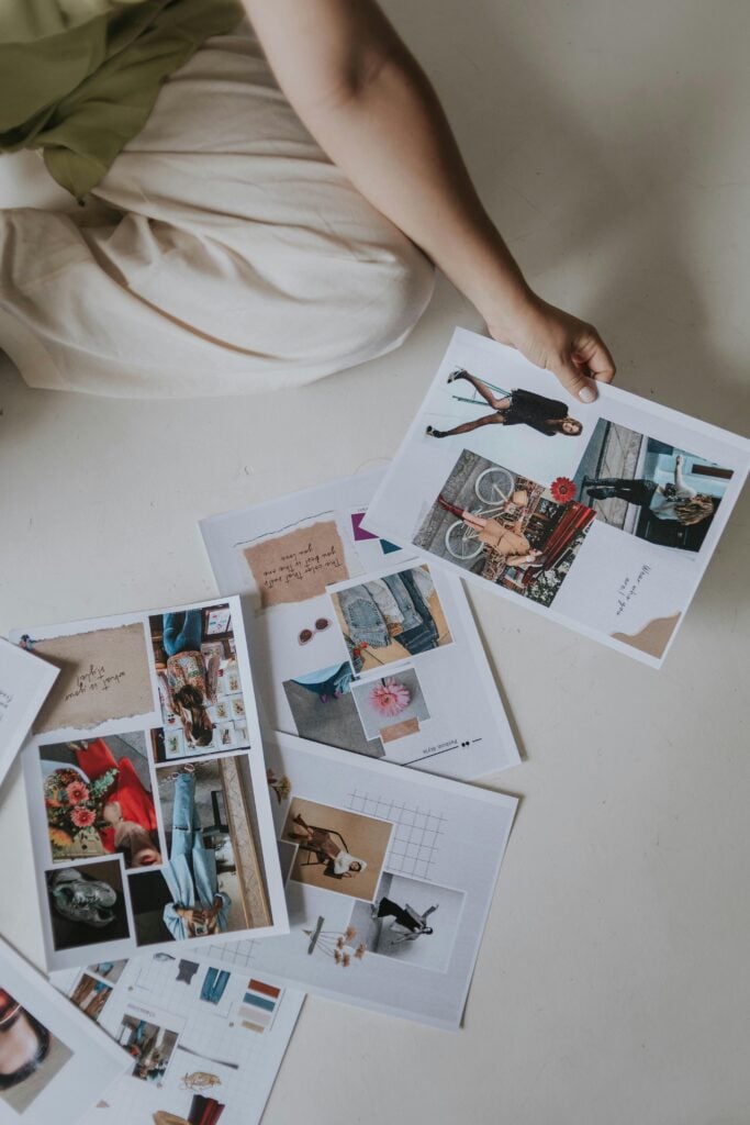 A woman siting on floor with photos and magazine clips putting things together for a vision.