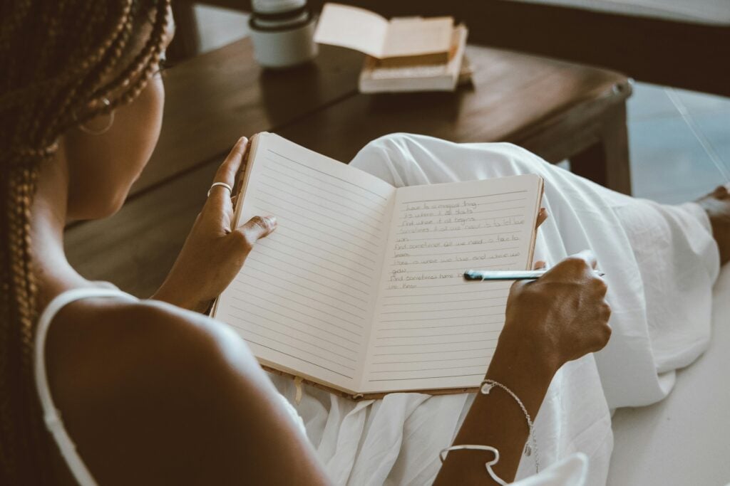 A woman sitting with journal and pen.