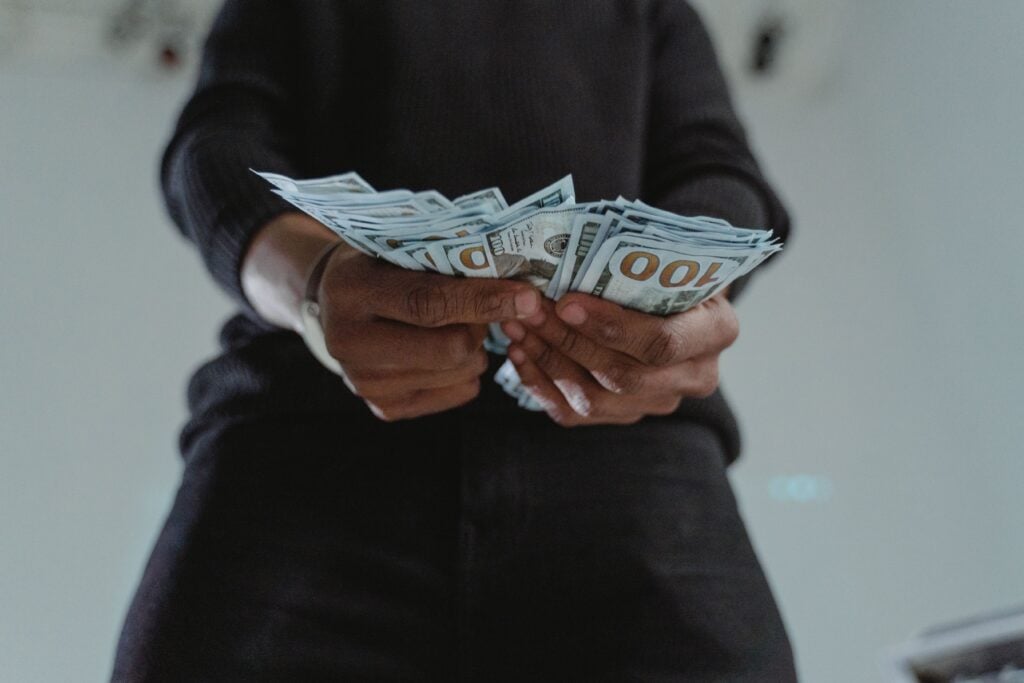A bunch of cash being held in a man's hands.