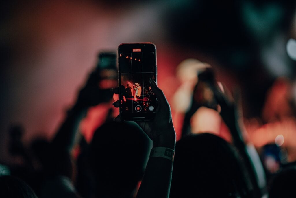 A crowd of people holding up their phones recording someone famous on stage.