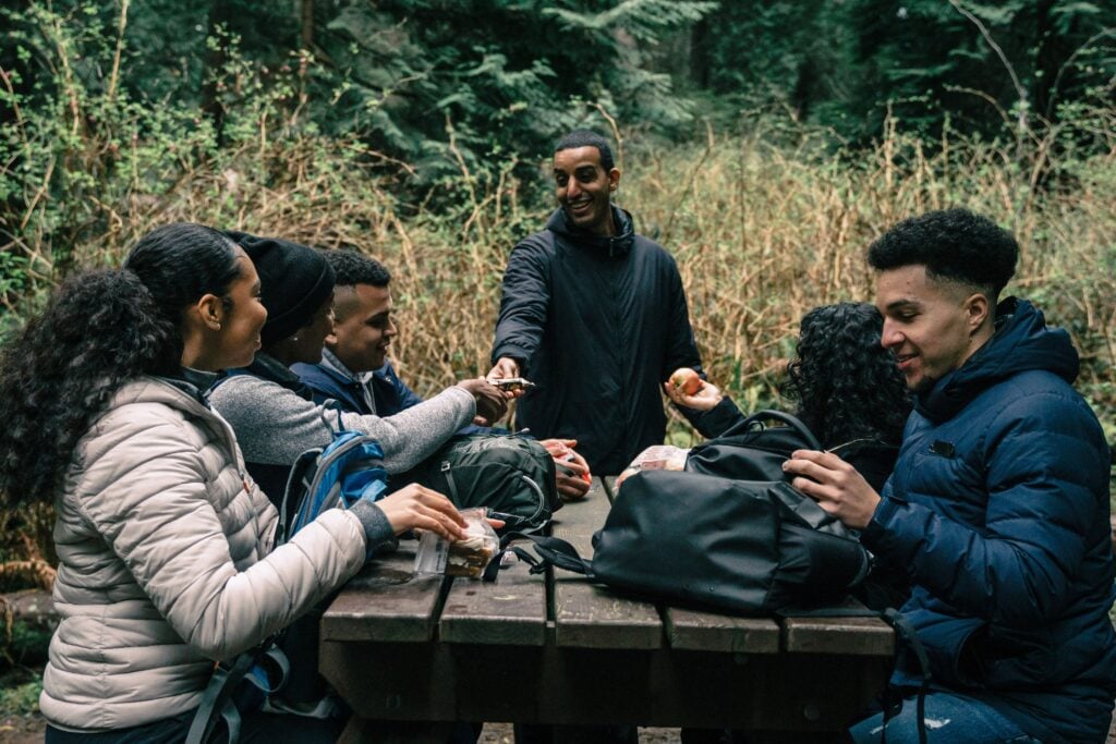 A group of people fellowshipping at a table with food.