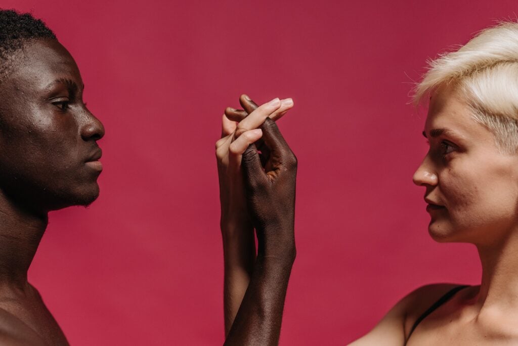 a black man and white women looking at each other holding hands.